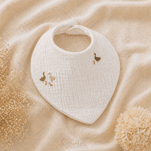 Bavoir bébé collection Sous les ailes douces en double gaze motif oies posé sur tissu beige doux