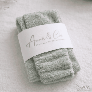 Bandeau maquillage vert de gris en éponge, fait main, présenté plié avec étiquette sur fond textile naturel