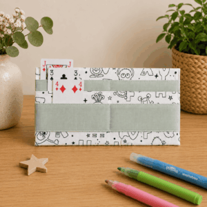 Porte-cartes de jeu à colorier pour enfant en tissu, déplié avec cartes à jouer maintenues par des bandes de tissu.